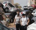 Una pareja con su bebé camina entre una montaña de coches hacinados tras las inundaciones sufridas en la localidad valenciana de Paiporta.